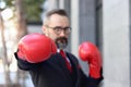 Senior mature businessman wearing red boxing gloves or mitt punch, metaphors about fight business for successful, elderly man