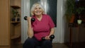 Senior mature grandmother woman doing weightlifting training workout dumbbell exercising at home Royalty Free Stock Photo