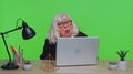 Senior mature older business woman hiding behind laptop computer, making funny face, fooling around