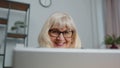 Senior businesswoman wears glasses working at home office, online webinar using laptop computer Royalty Free Stock Photo