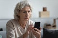 Senior mature retired woman reading unpleasant news in social media.