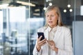 Senior mature woman boss at workplace received online notification message on phone with bad news, financier Royalty Free Stock Photo