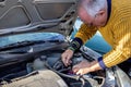 Senior mechanic worker checking and changing a car battery.