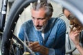 Senior mechanic working on bicycle woman watching Royalty Free Stock Photo