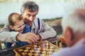 Senior men having fun and playing chess at park Royalty Free Stock Photo