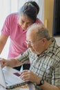 Senior man and his caregiver with laptop at home spending time togheter