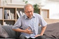 Senior men holding his stomach feeling pain while sitting on the sofa at home. Asian man having stomachache with isolated gastric