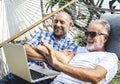 Senior men lying on a hammock using a laptop Royalty Free Stock Photo