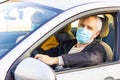 Senior man in a medical face mask driving a car. Coronavirus pandemic concept. Road trip, travel and old people concept - happy se Royalty Free Stock Photo