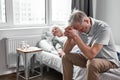 upset senior man sits with her sick ill wife lying on bed Royalty Free Stock Photo