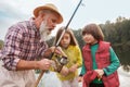 Senior man fishing on lake with his grandchildren Royalty Free Stock Photo