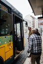 Senior men waiting to enter yellow public transportation bus at central station Royalty Free Stock Photo