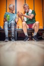 Senior man and woman sitting in gym locker room, talking and sharing an apple Royalty Free Stock Photo