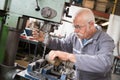 senior metal worker using industrial drilling machine in workshop Royalty Free Stock Photo