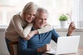 Senior middle aged happy couple embracing using laptop together Royalty Free Stock Photo