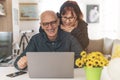 Senior middle aged happy couple embracing using laptop together -  smiling elderly family reading the news and shopping online Royalty Free Stock Photo