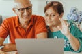 Senior middle aged happy couple embracing using laptop together - smiling elderly family reading the news and shopping online from Royalty Free Stock Photo