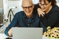 Senior middle aged happy couple embracing using laptop together - smiling elderly family reading the news and shopping online from Royalty Free Stock Photo