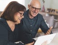 Senior middle aged happy couple embracing using tablet together -  smiling elderly family reading the news and shopping online Royalty Free Stock Photo