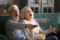 Elderly husband and wife cheering favorite sport team.