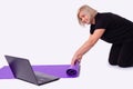 Senior middle-aged sporty slim woman preparing mat for online fitness training with modern laptop. Healthy lifestyle concept,