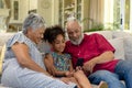 Senior mixed race couple sitting on the couch with their young  granddaughter Royalty Free Stock Photo