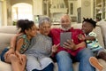 Senior mixed race couple sitting on the couch with their young grandson and granddaughter Royalty Free Stock Photo