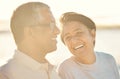 A senior mixed race couple walking together on the beach smiling and laughing on a day out at the beach. Hispanic Royalty Free Stock Photo