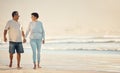 A senior mixed race couple walking together on the beach smiling and laughing on a day out at the beach. Hispanic Royalty Free Stock Photo