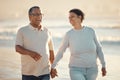 A senior mixed race couple walking together on the beach smiling and laughing on a day out at the beach. Hispanic Royalty Free Stock Photo