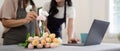 Senior mother and adult daughter happy on the table while arrange flowers in a vase together using laptop computer Royalty Free Stock Photo