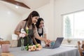 Senior mother and adult daughter happy on the table while arrange flowers in a vase together using laptop computer Royalty Free Stock Photo