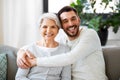 Senior mother with adult son hugging at home