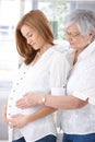 Senior mother embracing pregnant daughter smiling