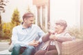 Senior mother and son talking while sitting on a wicker sofa outdoor
