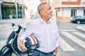 Senior motorcyclist man smiling happy holding moto helmet at the city