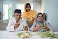 senior muslim couple and daughter making ketupat for eid fitr mubarak