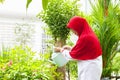 Senior muslim woman watering flower with can