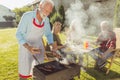 Senior neighbors grilling meat and relaxing outdoors