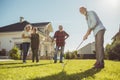 Senior neighbors having fun playing mini golf in the backyard