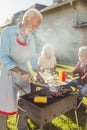 Senior neighbors making barbecue in the backyard