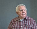 Senior octogenarian man in plaid with gray background