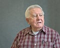 Senior octogenarian man in plaid with gray background