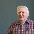 Senior octogenarian old man in plaid with gray background