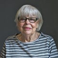 Senior octogenarian woman in striped top with gray background