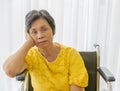 A senior old Asian woman sitting in wheelchair and with lonely feeling and waiting for someone to visit and take care of her with Royalty Free Stock Photo