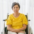 A senior old Asian woman sitting in wheelchair and with lonely feeling and waiting for someone to visit and take care of her with Royalty Free Stock Photo