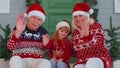 Senior old couple grandparents with grandchild girl kid waves hand hello, hi near Christmas house Royalty Free Stock Photo