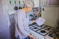 Senior old housewife at home and examines gas and electricity bills