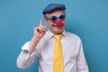 Senior old man with clown nose smiling pointing uo giving advice